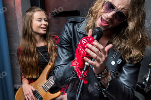 Preview: man singing in microphone with woman playing guitar, hard rock music concept