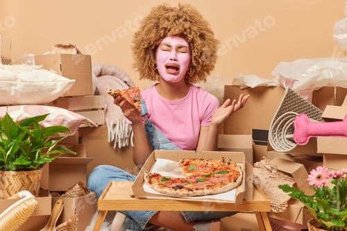 Preview: Frustrated crying woman applies beauty mask on face to reduce blackheads eats appetizing pizza sits