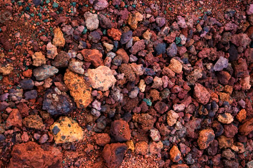 Preview: Red and pink rough volcanic stones in a quarry in Iceland. Textured background