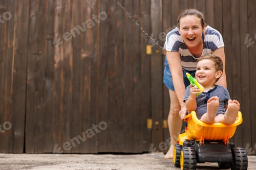 Preview: Mother having fun pushing child in toy truck