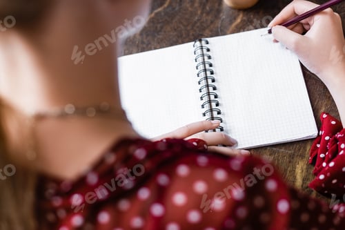 Preview: selective focus of student writing in notebook with pencil in apartment