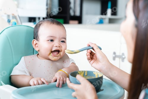 Preview: Baby enjoy and eating porridge in high chair.