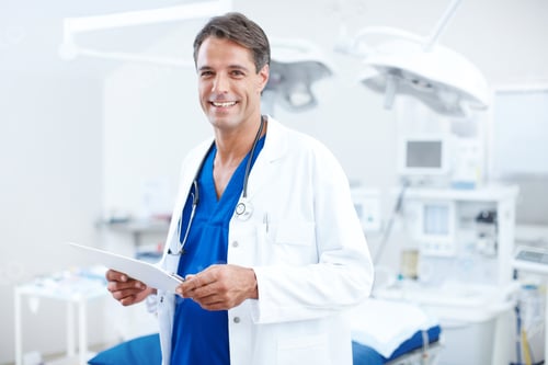 Preview: Smiling Man Doctor in Surgery Room Holding Chart