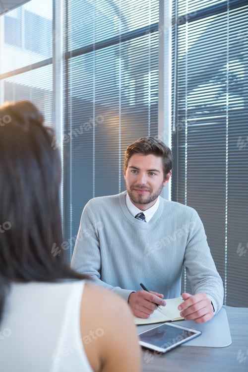 Preview: Male executive writing in organizer during meeting