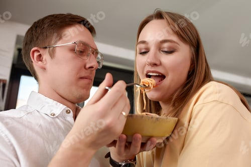 Preview: Smiling loving husband feeding wife, young couple enjoying tender moment, romantic date, having fun