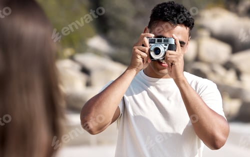 Preview: Pose for the picture. Shot of a young man taking pictures of his girlfriend at the beach.
