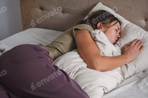 Preview: Woman peacefully sleeping with pillow in cozy bedroom setting.