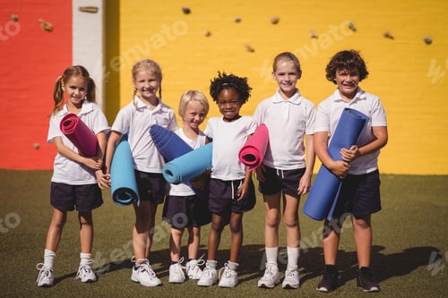 Preview: Portrait of smiling schoolgirls standing with exercise mat