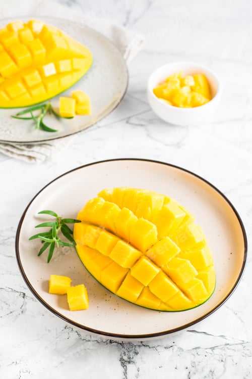 Preview: Ripe sliced mangoes on plates on the table. Tropical fruit. Vertical view