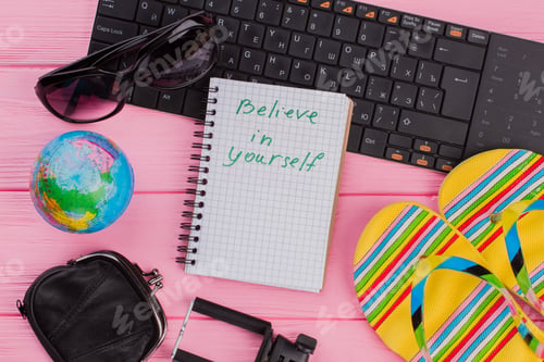 Preview: Believe in yourself on notebook with woman's traveler accessories.
