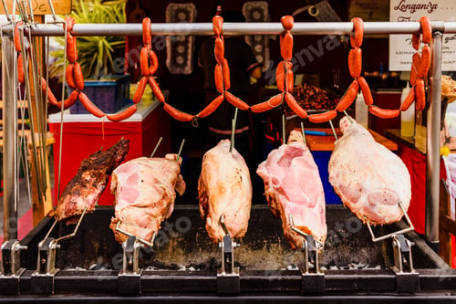 Preview: Whole pork hams roasting on a barbecue.