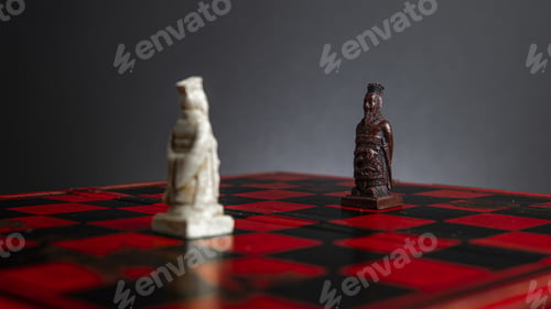 Preview: Closeup of the white and black king chess pieces on a red chessboard against a gray background
