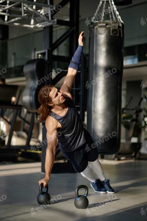 Preview: Muscular sportsman doing cross training kettlebell routine at fitness club