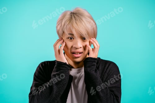 Preview: Frightened asian man shocked isolated over blue background. Stressed and depressed korean guy