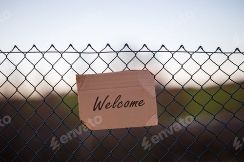 Preview: Closeup shot of refugees welcome sign on a metallic wired fence
