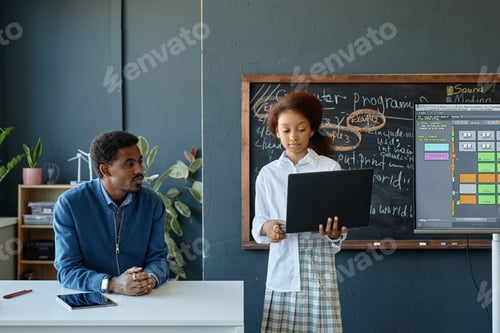 Preview: of Black Girl Holding Laptop Giving Presentation in Class with Teacher Watching