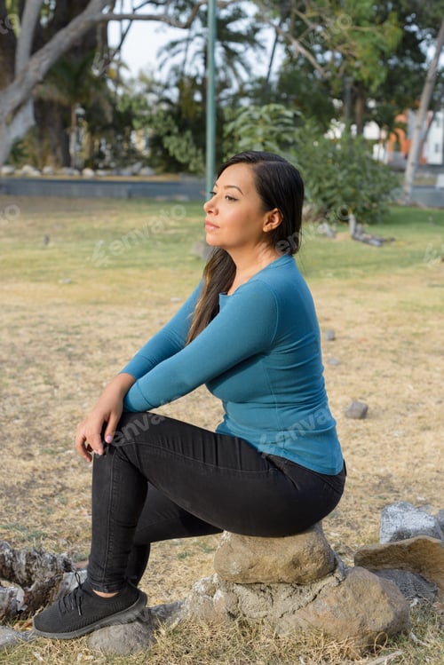 Preview: Woman seated in a public park with an attitude of preoccupation, pensive.
