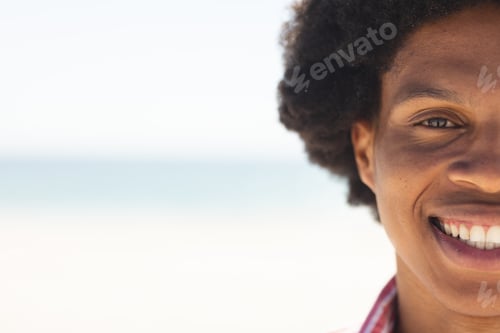 Preview: Close-up of a young African American man smiling at the beach, with copy space