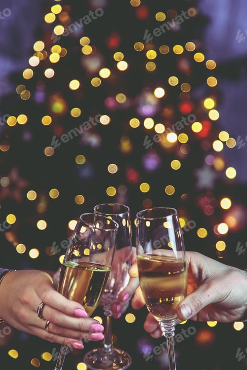 Preview: Champagne in hand against the background of the Christmas tree. People. Selective focus.