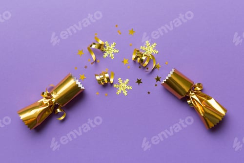 Preview: Christmas crackers with shiny confetti on color background, top view, copy space