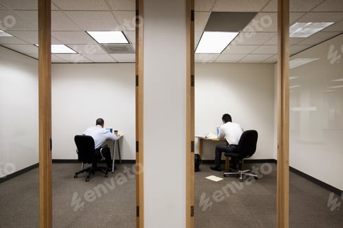 Preview: A view of two businessmen working on opposite sides of a wall in two different office spaces.