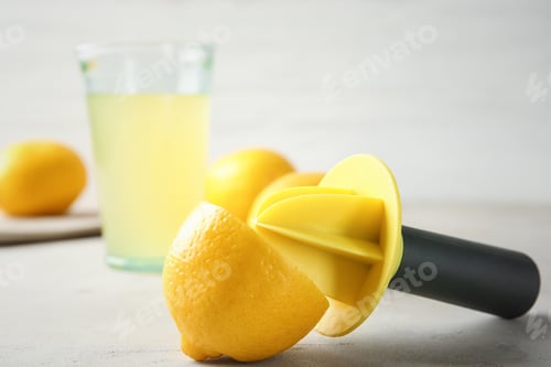Preview: Fresh ripe lemon and reamer on table