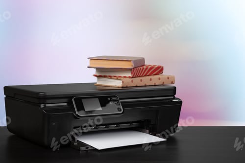Preview: Stack of books and home printer against blurred background