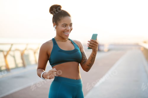 Preview: Smiling Woman in Sportswear Looks at Phone Outdoors