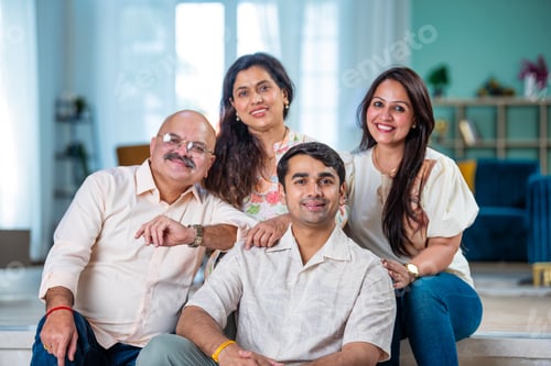 Preview: Portrait of happy Indian family of four sitting in modern living room