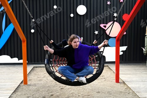 Preview: A girl swings on a round swing on the playground