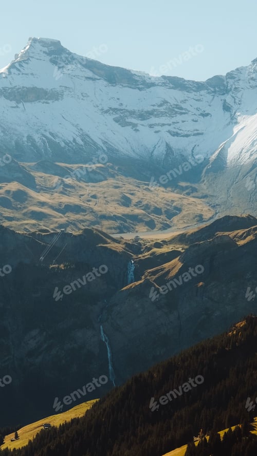 Preview: Vertical image of snow-covered mountain peaks in the far distance, a mountainside in the foreground
