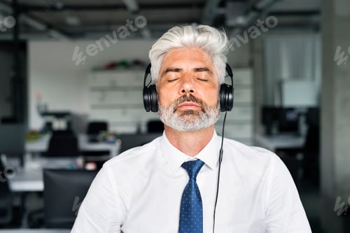 Preview: Mature businessman with headphones in the office.