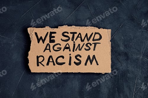 Preview: We stand against racism text on cardboard on dark background