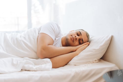 Preview: Positive attractive male dreaming with a smile on his face while lying on a soft pillow