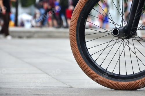 Preview: A BMX bike wheel against the backdrop of a blurred street with cycling riders