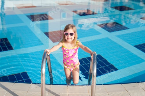 Preview: Summer vacation concept. Little cute girl in sunglasses near a swimming pool