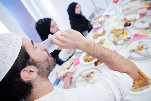 Preview: Muslim family having Iftar dinner drinking water to break feast