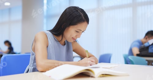 Preview: Young woman studying at library