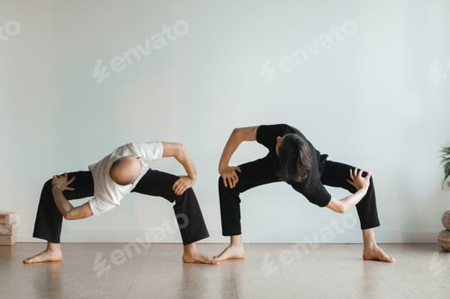 Preview: two young athletes practice yoga in the gym. Joint training, indoors, studio. The concept of a