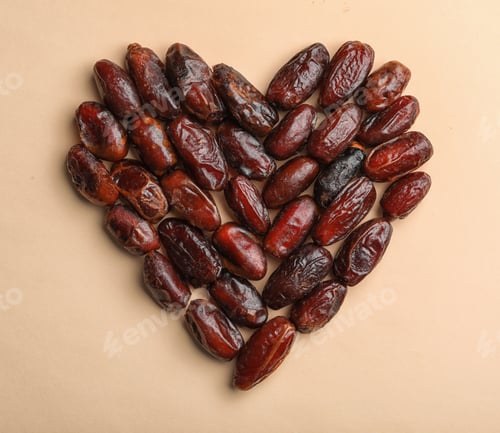 Preview: Heart shaped pile of sweet dried date fruits on color background, top view with space for text