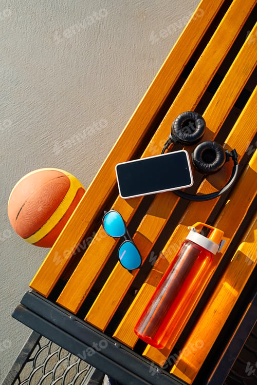 Preview: Basketball, Smartphone, Headphones, Sunglasses and Water Bottle on Wooden Bench.