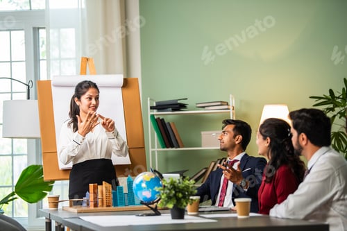 Preview: Group Of Businesspeople Looking At Young Indian asian Business person Giving Presentation In Meeting
