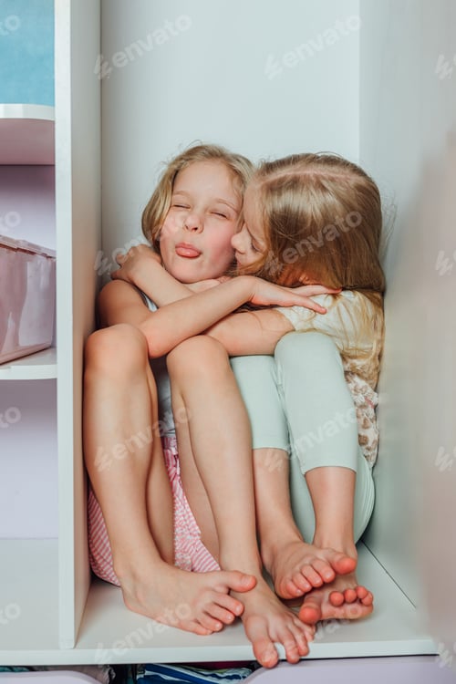 Preview: Two little girlfriends, sisters play fashion, hide and seek. girl sits in the closet, laughs, smile