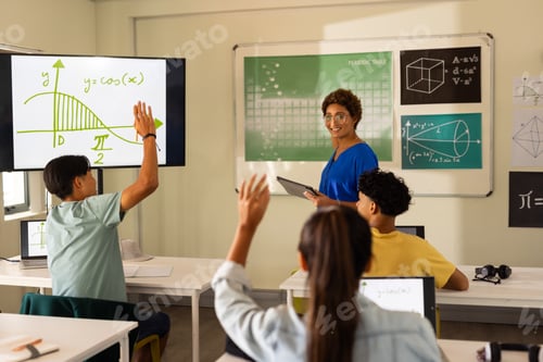 Preview: In high school, students raising hands in classroom while teacher explains math lesson