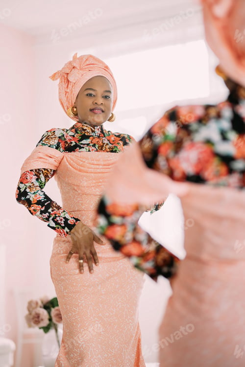 Preview: Studio shot of joyful pretty African lady wearing stylish pink dress with traditional print and