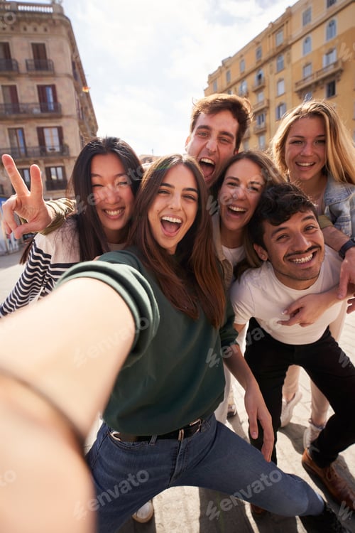 Preview: Vertical selfie of group young multi-ethnic friends having fun together outdoors. Excited people.