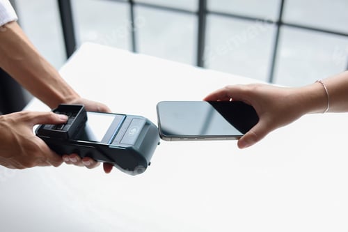 Preview: People using a smartphone to pay by holding close to a point-of-sale (POS) terminal.