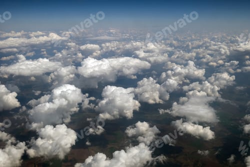 Preview: Aerial view from airplane window of white puffy clouds on bright sunny day.