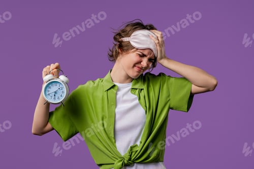Preview: Woken up by alarm clock sleepy young woman holding it in hand. Violet background.