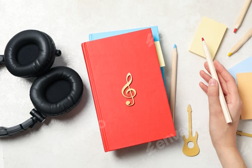 Preview: Headphones, books, pencils and female hand on light background, top view
